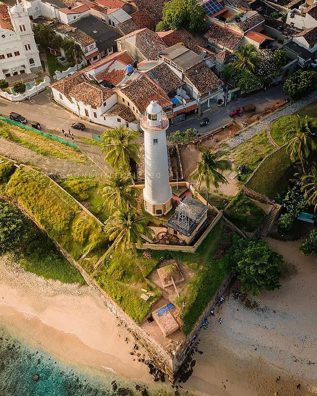 Galle Fort lighthouse seen from above with palms and the beach