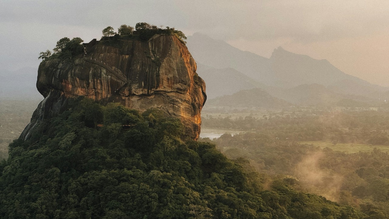 Sigiriya Lion Rock rising above misty jungle at sunrise